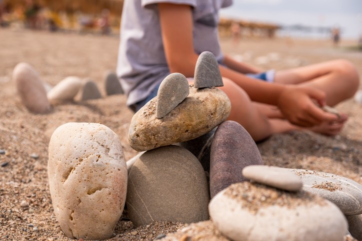 enfant qui joue sur la plage en été avec des cailloux. Photo illustrative